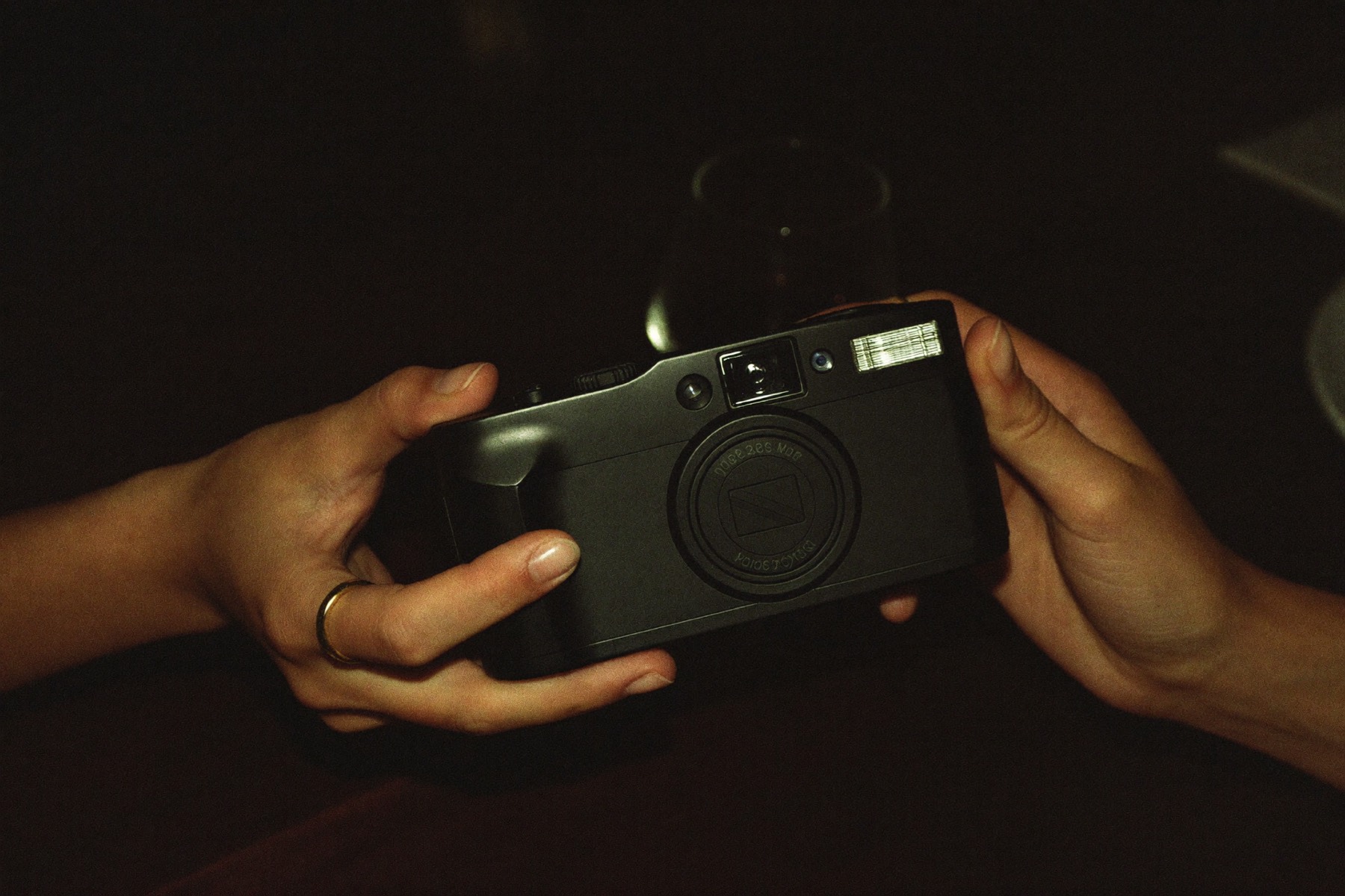 Hands passing a disposable camera. Atmosphere only — not a guest frame.
